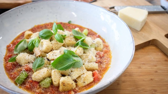 Gnocchi mit Tomatensoße, Parmesan und Basilikum auf einem großen Teller serviert. © NDR Foto: Tarik Rose