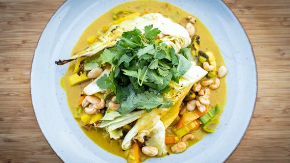 Geschmorter Ofen-Spitzkohl mit Gemüse-Curry auf einem Teller serviert. © NDR Foto: Tarik Rose