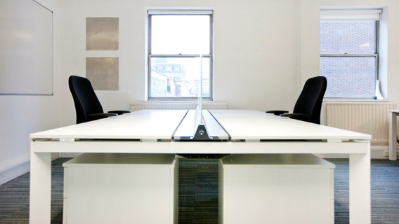 Ein Büro mit zwei gegenüberliegenden Schreibtischen und Stühlen © mauritius images / Alamy Stock Photos / YAY Media 