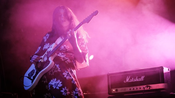 Eine Frau mit Gitarre in rosa Nebel © NDR 