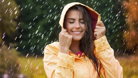 Junge Frau steht mit einer Regenjacke bekleidet im Regen. © Fotolia.com Foto: gpointstudi