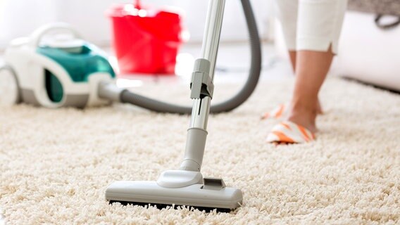 Staubsauger saugt einen Teppich ab. © Fotolia.com Foto: didesign