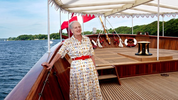Königin Margrethe II. lächelt und steht auf einem edlen Holzboot mit dänischer Flagge © Keld Navntoft, Kongehuset Foto: Keld Navntoft, Kongehuset