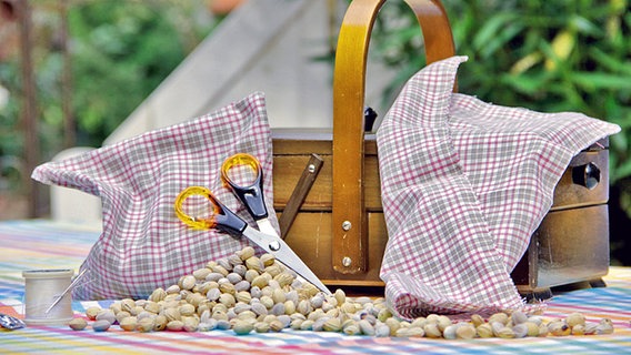Auf dem Tisch liegt Material für Kirschkernkissen: Stoff, Kirschkerne und Nähzubehör. © NDR Foto: Mirella Papparlardo