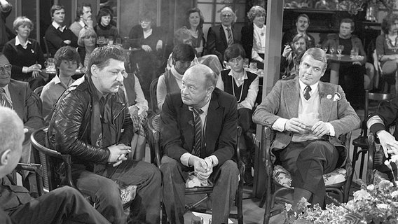 Moderator Michael Lentz (Mitte) spricht mit dem Regisseur Rainer Werner Fassbinder (links). NDR Talk Show vom 12.12.1980 © NDR/Detlef Drischel 