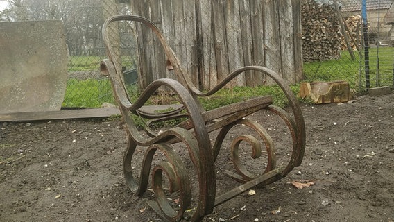 Ein alter, verfallener Schaukelstuhl steht im Garten. © NDR/Jana Weber 