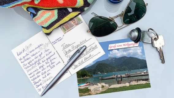 Postkarte, Brille, Schlüssel, Handtuch und Sonnencreme liegen auf einer Fläche. © Christine Raczka Foto: Christine Raczka