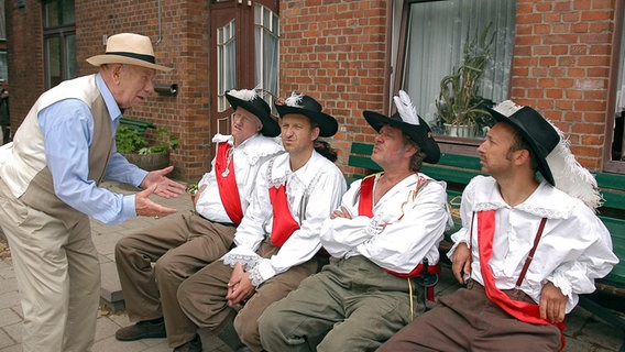 Szenenbild aus der 17. Büttenwarder-Folge "Karneval": Bürgermeister Schönbiehl, Shorty, Adsche, Brakelmann und Kuno sitzen vor dem Dorfkrug. © NDR/Nicolas Maack Foto: Nicolas Maack