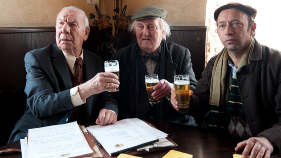 Szenenbild aus der 52. Büttenwarder-Folge "Patchwork": Bürgermeister Schönbiehl, Onkel Krischan und Kuno sitzen am Tisch im Dorfkrug. © NDR/Nico Maack Foto: Nico Maack