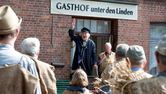 Onkel Krischen spricht vorm Dorfkrug zu seinen Untertanen. © NDR/Nicolas Maack 