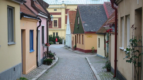 Eine schmale Kopfsteinpflaster-Straße mit kleinen bunten Häusern gesäumt. © HarmM 
