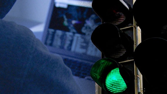 Eine auf "Grün" geschaltete Ampel in der Dunkelheit und ein Laptop © NDR 