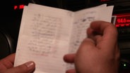 Eine Liste mit arabischen Namen wird in die Kamera gehalten.  