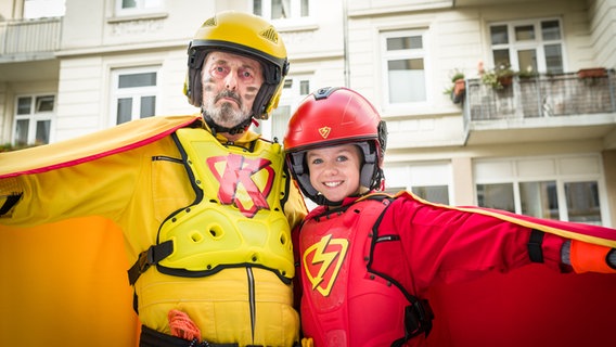 Klabauterman (Peter Rühring) und Roter Blitz (Lilly Barshy) verkleidet in Superhelden-Kostümen. © NDR/Studio HH Foto: Boris Laewen