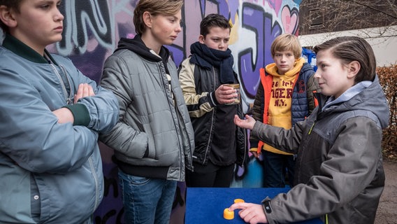 Yanis (Tom Philipp, rechts) kassiert beim Hütchenspiel ab © NDR/Boris Laewen Foto: Boris Laewen