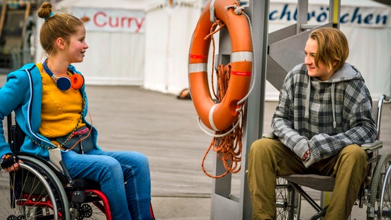 Pippa lächelt einen Jungen an, der ihr gegenüber auch im Rollstuhl sitzt. © NDR/Letterbox Foto: Boris Laewen