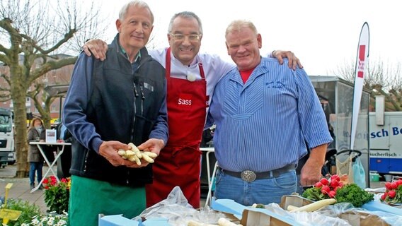 Rainer Sass (Mitte) steht mit Karl-Heinz Schween (links) und Bernd Keller auf dem Reinbeker Wochenmarkt. © NDR/dmfilm Foto: Florian Kruck