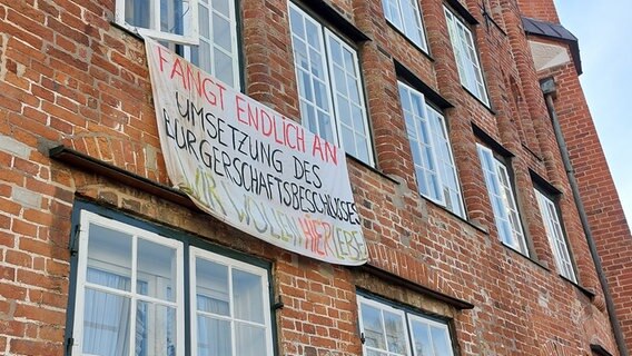 Frontansicht des Heiligengeisthospitals in Lübeck, Transparent mit der Aufschrift "Wir wollen hier Leben" © NDR Foto: Mechthild Maesker