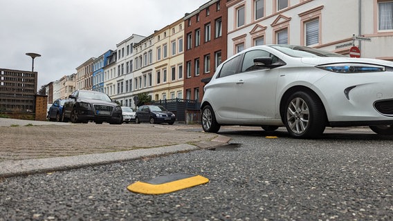 In einer Wohnstraße stehen Pkw, auf dem Boden sind Parksensoren montiert. © NDR Foto: Phillip Kamke