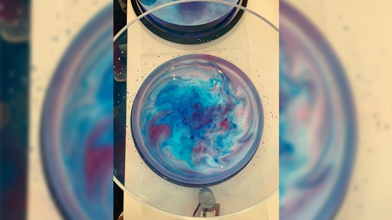 Blick in ein Glas mit schillernden Farben. © NDR Foto: Friederike Schneider