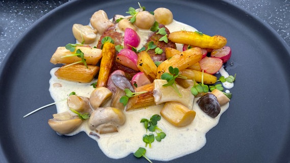 Kartoffelrösti mit Frühlingsgemüse und Pilzrahmsoße auf einem Teller angerichtet. © NDR 