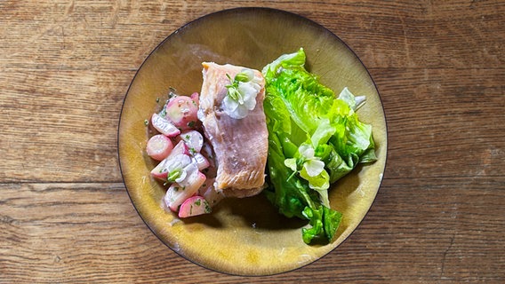 Saibling mit Radieschengemüse und Salat auf einem Teller angerichtet. © NDR 
