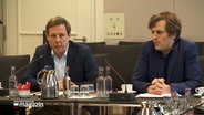 Thomas Losse-Müller, SPD-Fraktionsvorsitzender, sitzt bei einer Sitzung an einem Tisch neben einem anderen Mann. © NDR 