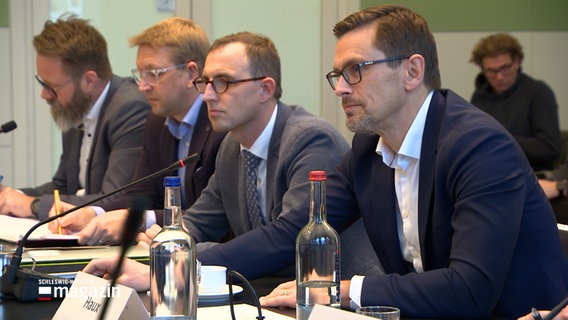 Christofer Haux, Geschäftsführer Northvolt Deutschland, sitzt mit anderen Beteiligten an einem Tisch im Wirtschaftsausschuss im Kieler Landtag. © NDR 