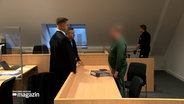 Ein Angeklagter unterhält sich mit seinem Verteidiger in einem Gerichtssaal. © NDR 
