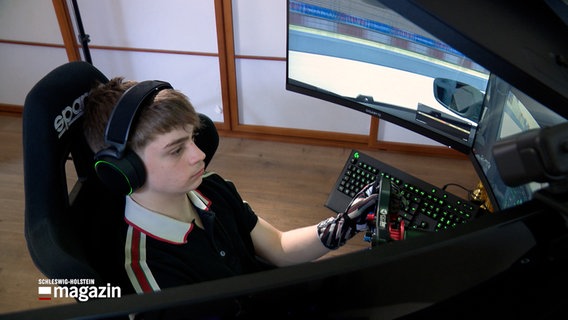 Ein junger Mann sitzt in einem Rennwagen-Simulator und trainiert. © NDR 