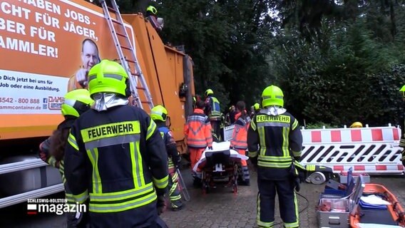 Einsatzkräfte der Feuerwehr und des Rettungsdienstes stehen an einem Müllwagen in Schnakenbek im Kreis Herzogtum Lauenburg. © NonstopNews 