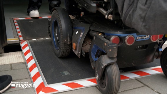 Ein elektrischer Rollstuhl fährt aus einem Linienbus an einer Haltestelle. © NDR 