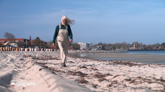 Eine ältere Frau geht an einem Strand spazieren. © NDR 