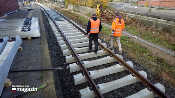 Zwei Bauarbeiter laufen über die Gleisen einer Bahnerneuerung © NDR Schleswig-Holstein Magazin 