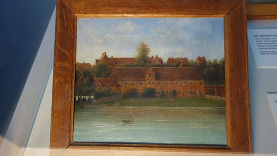 Ein Gemälde, auf dem die Kieler Gebäranstalt am Wasser zu sehen ist, steht auf einem Tisch.  Foto: screenshot