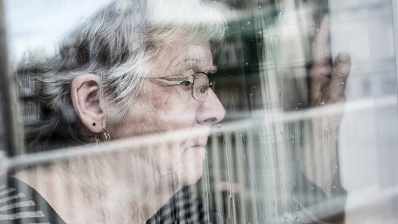 Eine ältere Frau schaut aus einem Fenster. © fotolia.com Foto: pololia
