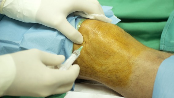 Ein Arzt gibt einem Patienten eine Spritze ins Kniegelenk. © Colourbox Foto: Edward Olive