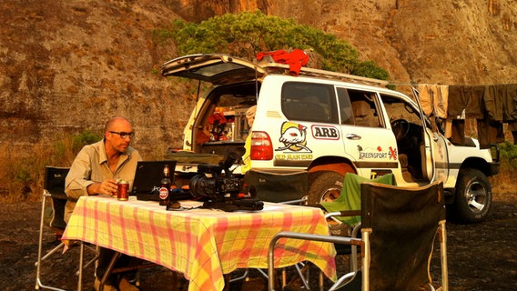 Korrespondent Ulli Neuhoff sitzt an einem Campingtisch am Laptop  