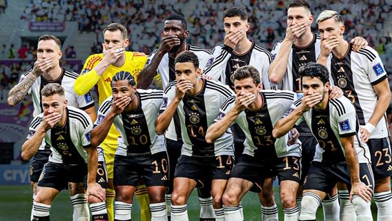 Die Deutschen Nationalspieler halten sich beim Gruppenfoto vor dem Japan-Spiel die Hände vor den Mund. © picture alliance 