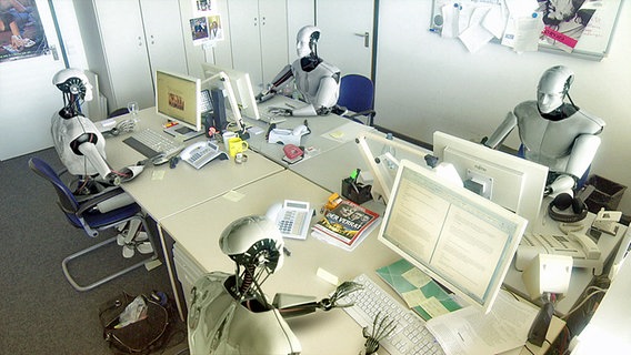 Roboter sitzen an Schreibtischen mit PCs © NDR 