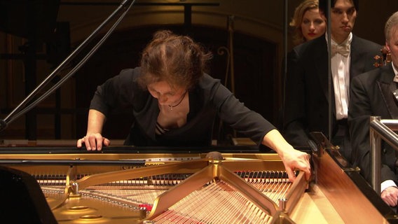 Die Pianistin Ulrike Payer greift bei einem Konzert mit dem  NDR Sinfonieorchester in den offenen Konzertflügel  