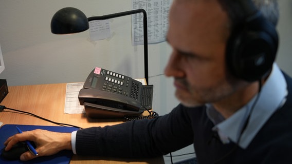 Ein Ermittler trägt bei der Telefonüberwachung Kopfhörer. © NDR/Kevin Finke 