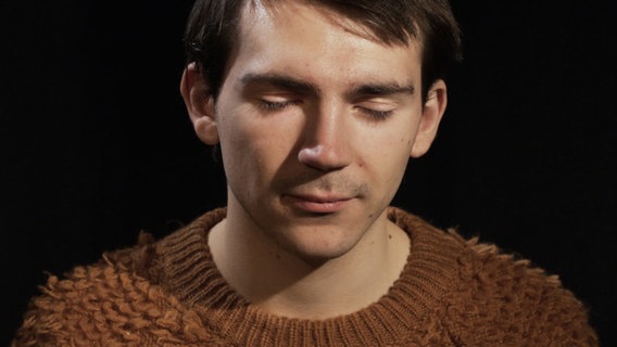 Ein Mann mit braunem Pullover hat die Augen geschlossen. © NDR 