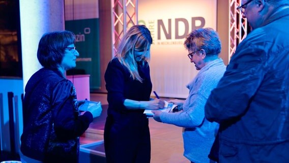Kim Fisher gibt Autogramme auf der Bühne im Foyer des Funkhauses Schwerin. © NDR Info Foto: Jenny von Gagern