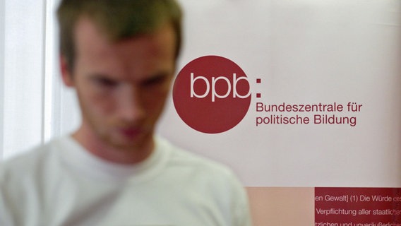 Ein junger Mann vor dem Logo der Bundeszentrale für politische Bildung © picture alliance / photothek Foto: Liesa Johannssen