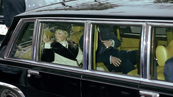 6. November 1987: Bei ihrem Besuch in Hamburg winkt Diana Menschen am Straßenrand aus einer dunklen Limousine zu. © Picture-Alliance / dpa 