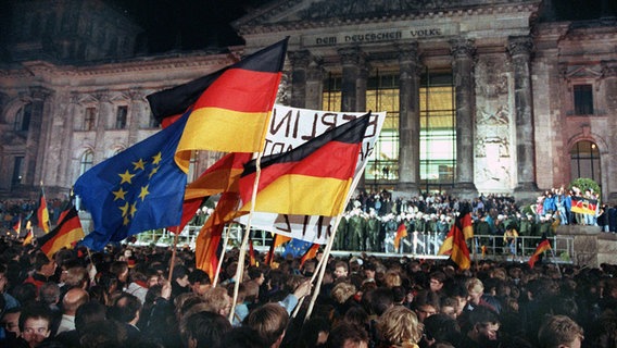 Eine Menschenmenge feiert am 3. Oktober 1990 vor dem Reichstagsgebäude in Berlin die deutsche Wiedervereinigung. © picture alliance / dpa Foto: Wolfgang Kumm