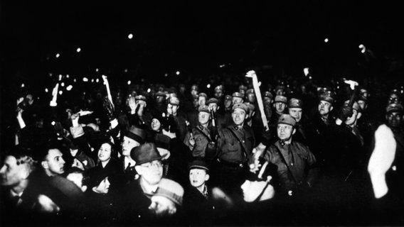 Angehörige der SA marschieren am 30.01.1933 mit Fackeln durch die von Zuschauern gesäumten Straßen von Berlin © dpa 