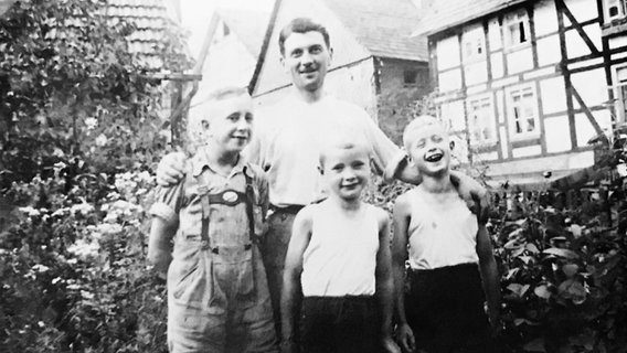 Das Bild zeigt Jean, einen erwachsenen Mann, mit drei Jungen, den Brüdern Münder. © Walter Münder 