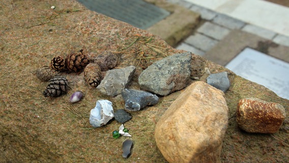 Menschen mit kleinen Steinen Zeichen des stillen Gedenkens auf einem Gedenkstein auf dem Ehrenfriedhof am Lüneburger Stadtrand abgelegt. © NDR Foto: Lars Gröning